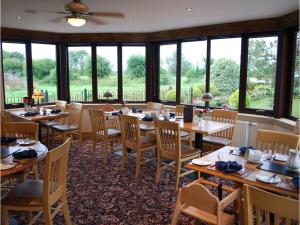 un restaurante con mesas y sillas de madera y ventanas en Double-Gate Farm en Wells