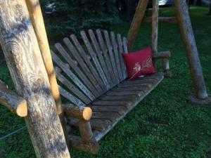 a wooden bench with a red pillow on the grass at Dragonfly Bed and Breakfast in Antioch