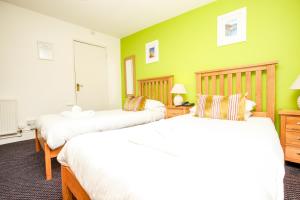 two beds in a room with green walls at Driftwood Spars in St. Agnes