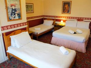 a hotel room with two beds and two tables at A MAIDEN REST in Weymouth