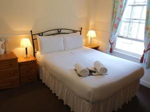 a bedroom with a large white bed with towels on it at A MAIDEN REST in Weymouth