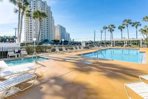 a swimming pool with lounge chairs and palm trees at Grand Caribbean East & West in Pensacola