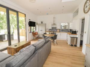 a living room with a gray couch and a kitchen at The Leat in Redditch +21 photos