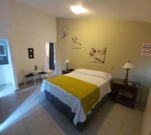 a bedroom with a large bed with a yellow blanket at Apart Hotel Turey in Santo Domingo