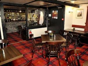 a restaurant with tables and chairs and a bar at Elphinstone Hotel in Biggar