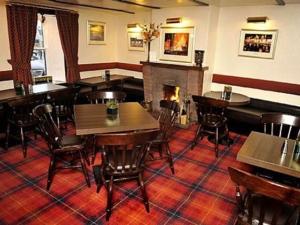 a restaurant with tables and chairs and a fireplace at Elphinstone Hotel in Biggar