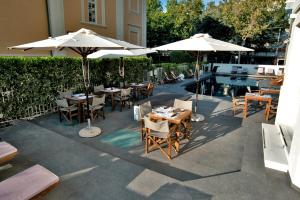 a patio with tables and umbrellas next to a pool at Le Rose Spa Hotel in Rimini +128 photos