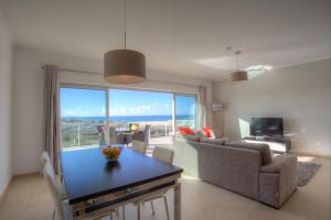 a living room with a table and a large window at The Beachfront - Praia D'El Rey Golf & Beach Resort in Casal da Lagoa Seca