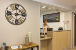 a woman standing in an office with a large clock on the wall at Citadines Castellane Marseille in Marseille