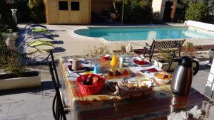 una mesa con comida junto a una piscina en l'oustau bonur, en Bourg-Saint-Andéol