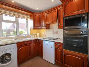 a kitchen with wooden cabinets and a washer and dryer at Summerfields in Uttoxeter