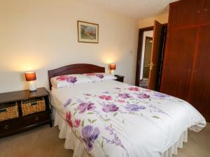 a bedroom with a bed with purple flowers on it at Summerfields in Uttoxeter