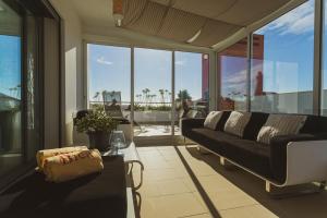 a living room with a black couch and large windows at Bica, luxury heated penthouses with jacuzzi and large terrace in Baleal in Baleal
