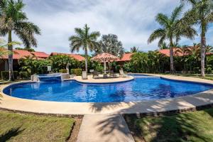 a large swimming pool in a yard with palm trees at Claudia Villagge in Guanacaste