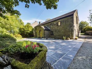 una antigua casa de piedra con un jardín delante de ella en Foxlow Coach House, en Buxton