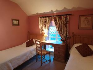 a bedroom with two beds and a desk and a window at Kilmokea Garden Suite in New Ross