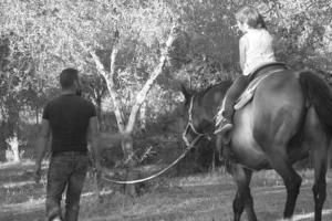 恩納的住宿－羅西別墅，一位马匹上带领小女孩的人