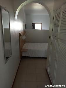 a small room with a bed and a door at Hotel Eira Da Pedra in Vila Nova de Milfontes