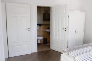 a bedroom with white doors and a bathroom with a sink at Gästehaus Burgblick in Neustadt-Glewe