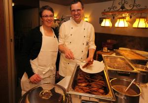 Een man en een vrouw die in een keuken eten klaarmaken. bij Hotel Geschermann in Sendenhorst