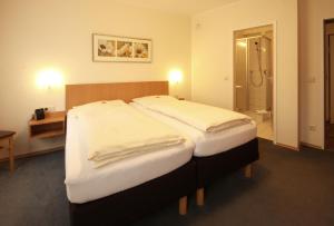 een hotelkamer met 2 bedden en een badkamer bij Hotel Geschermann in Sendenhorst