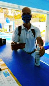 a man wearing a mask standing at a table with a bottle of medicine at Hostal Aruba in Atacames