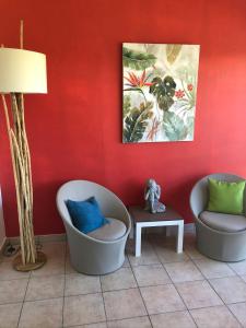 due sedie e un tavolo in una stanza con una parete rossa di Appartement de charme au bord de mer a Saint-François