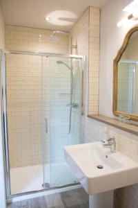 uma casa de banho com um lavatório e um chuveiro com uma porta de vidro em Gilpin Bridge Inn em Kendal