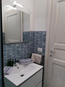 La salle de bains est pourvue d'un lavabo blanc et d'un miroir. dans l'établissement Piccola Dependance, à Syracuse