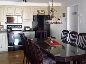 a kitchen with a dining table and a black refrigerator at Gite Chute Couette Cafe in Notre-Dame-du-Portage