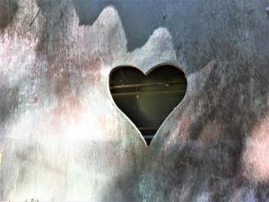 een hartvormig gat in de zijkant van een metalen muur bij Gites La Source in Le Calet