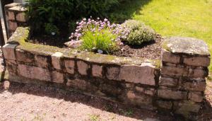 un mur en briques avec des fleurs dans un jardin dans l'établissement Gites de Montvaltin, à Le Breuil