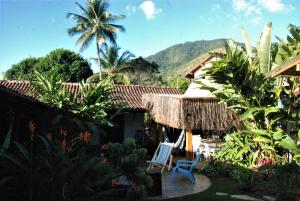 a house with two chairs and a thatched roof at Villa Adria in Ilhabela