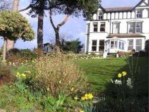 una gran casa blanca con un patio con flores en Glan Heulog en Conwy