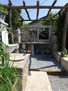 a stone fireplace in a garden with a wooden pergola at MAPLE place in Pivka