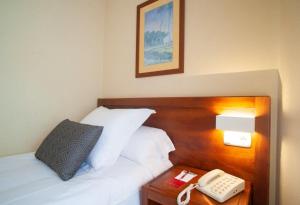 a hotel room with a bed with a phone on a table at Hotel San Lorenzo in Santiago de Compostela