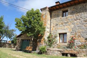 RedondoにあるLa Casa del Diezmo de la Montaña Palentinaの緑の扉と木のある古い石造りの家