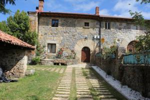 an old stone building with a door and a yard at La Casa del Diezmo de la Montaña Palentina in Redondo