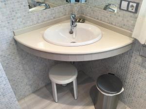 a bathroom with a white sink and a stool at Complexo Alameda in Viveiro