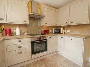 a kitchen with white cabinets and a red appliance at Anvil Cottage in Near Sawrey