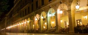 a lit up building with people sitting outside at night at City Marina in Corfu Town