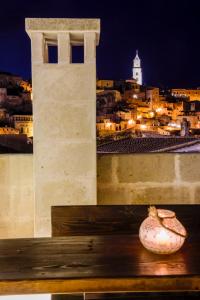 un vaso seduto su una panchina di fronte a una torre di L'Artiere Dimore nei Sassi a Matera
