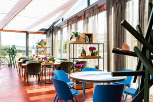 ein Restaurant mit Tischen, Stühlen und Fenstern in der Unterkunft HIRSCHEN OBERKIRCH - Design Boutique Hotel in Oberkirch