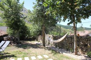 a hammock in a garden next to a stone wall at La Casa del Diezmo de la Montaña Palentina in Redondo