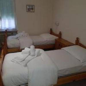 two beds in a room with white sheets at Hotel Topazio in Lurisia