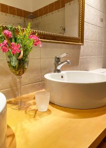 a bathroom with a sink and a vase of flowers on a counter at Seaside "Stone & Light Villa" close to Aegina City in Khlóï