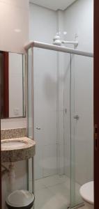 uma casa de banho com uma cabina de duche em vidro e um lavatório. em Hotel Castro em Palmas
