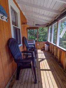 3 chaises assises sur la terrasse couverte d'une cabine dans l'établissement Tracadie Cottages, à York