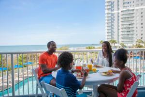 eine Gruppe von Menschen, die auf einem Balkon am Tisch sitzen in der Unterkunft Sea Watch Resort in Myrtle Beach