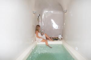 una donna seduta in una vasca da bagno con acqua di Abelis Canava Luxury Suites a Vóthon